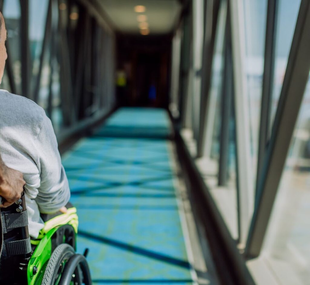A UK Airport assistant helps a passenger using a wheelchair board an aeroplane, showcasing compliance with UK air travel accessibility laws | accessairbility