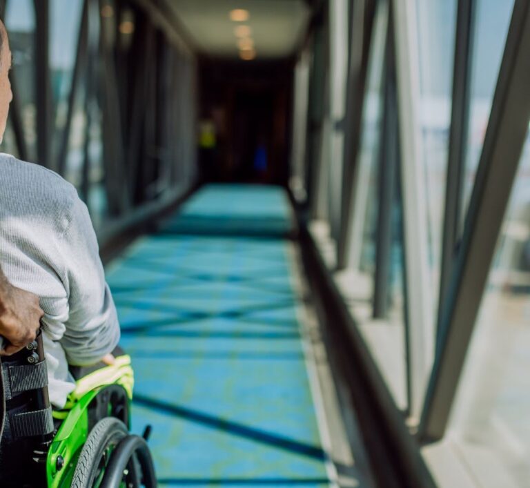 A UK Airport assistant helps a passenger using a wheelchair board an aeroplane, showcasing compliance with UK air travel accessibility laws | accessairbility